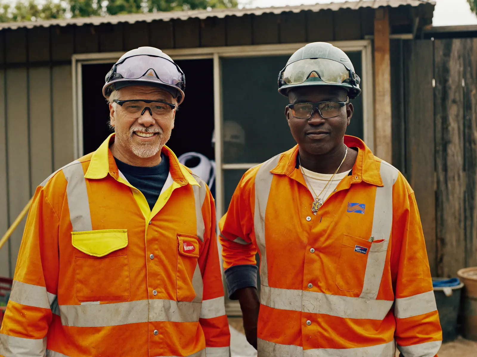 Two Australian tradies in hard hats and high-vis on a construction yard