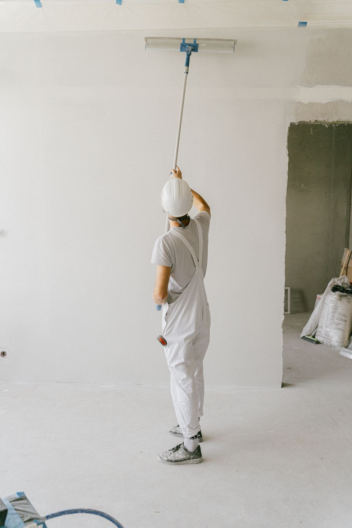 Person painting a wall with a roller — physical labour that Australians might call hard yakka
